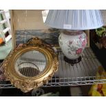 A FANCY GILT FRAMED OVAL BEVEL PLATE WALL MIRROR together with a rose decorated ceramic base table