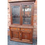 AN EARLY 20TH CENTURY OAK FINISHED BOOKCASE / DRESSER having fancy leaded twin doors, opening to