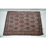 A PERSIAN RUG, cream ground with rows of vases of flowers and birds in rust red and blue to the