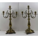 A PAIR OF DECORATIVE BRASS TWIN BRANCH TABLE CANDELABRA, triple sconce design, on baluster stems and