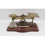 A BRASS LETTER SCALE ON A SERPENTINE WOOD BASE with a weight stack, bears an ivorine label, "
