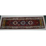 A PERSIAN DESIGN RUNNER, crimson ground with three geometric devices in blue, gold, crimson,