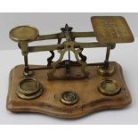 A BRASS POSTAL SCALE on polished wood serpentine fronted base, the weigh plate engraved with