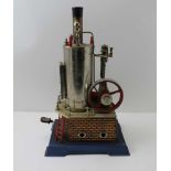 A WILESCO STATIONARY STEAM ENGINE, piston driven fly wheel on brick effect tin base and blue