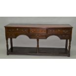 A GEORGE III OAK DRESSER BASE, the plank top over three cockbeaded drawers over a twin arch apron