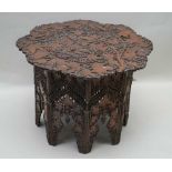 AN EASTERN CARVED WOOD OCCASIONAL TABLE, the top chip carved with leaves and berries, 73cm diameter,