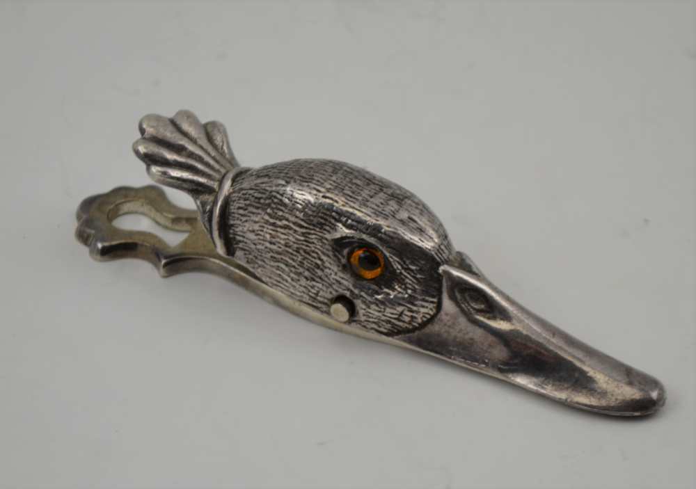 A PLATED CLIP IN THE FORM OF A DUCK'S HEAD, inset glass eyes, 12.5cm