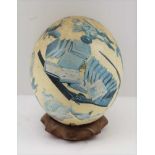 AN OSTRICH EGG having decoupage decoration of a country sports theme, raised upon a brass inlaid