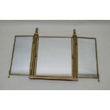 A BRASS FRAMED TRIPLE PLATE DRESSING TABLE MIRROR, with two cast lion finials, 56cm high