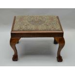 A GEORGIAN DESIGN WALNUT STOOL, raised on cabriole supports with ball & claw feet, tapestry