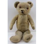 A "MERRYTHOUGHT" TEDDY BEAR, worn blonde plush with glass eyes, bears the early "Hygenic Toys" label