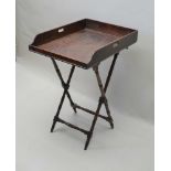 A GEORGE III MAHOGANY BUTLER'S TRAY, gallery sides with pierced handles, 54cm x 77cm, on a folding