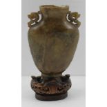 A CHINESE CARVED STONE VASE with mask shoulder handles, 10cm high, with carved wood stand