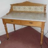 A 19TH CENTURY STRIPPED PINE MARBLE TOPPED WASHSTAND with tiled back, fitted two drawers raised on