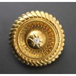 A 19th century YELLOW METAL BROOCH of ETRUSCAN DESIGN inset diamond to central boss, glazed frame to