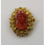 A PART BUCKLE, yellow metal filigree framing a carved coral mask cameo, 3cm x 2.5cm