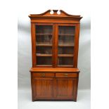 A LATE VICTORIAN WALNUT BOOKCASE, the base enclosed by a pair of raised and fielded panel doors over