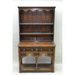 AN EARLY 20TH CENTURY OAK DRESSER of small proportions, having twin shelved plate rack back, on a