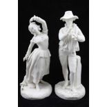 A PAIR OF LATE 19TH CENTURY CONTINENTAL PARIAN WARE FIGURES, in peasant costume, he plays the pipe