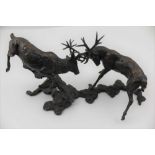A 20TH CENTURY CAST BRONZE OF TWO RUTTING STAGS, their antlers locked, on ground work base, 23cm x