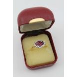 AN 18CT GOLD LADY'S RUBY & DIAMOND CLUSTER RING, the centre set four rubies, surrounded by sixteen