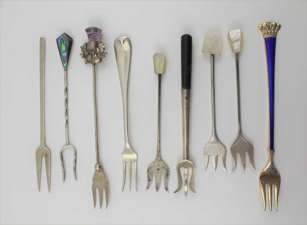 NINE VARIOUS SILVER AND WHITE METAL PICKLE FORKS, includes a blue enamel handled example with