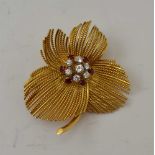 AN 18CT GOLD BROOCH, modelled as a flower. the centre inset a cluster of seven brilliant cut