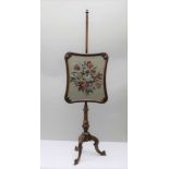 A 19TH CENTURY MAHOGANY FRAMED POLE SCREEN, raised on carved tripod supports, inset floral