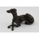 A 20TH CENTURY CAST BRONZE RECLINING LONG DOG, 9cm long