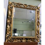 A CARVED AND GILDED FLORENTINE FANCY FRAME CONTAINING A MIRROR PLATE