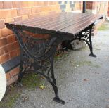 A PAINTED WOODEN SLAT TOPPED GARDEN TABLE on cast metal side supports