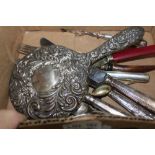 A BOX CONTAINING A SELECTION OF ODD CUTLERY, embossed back hand mirror, and associated items