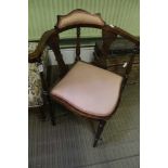 AN EARLY 20THV CENTURY WOODEN FRAMED CORNER ARMCHAIR, having textured upholstered back and seat pad
