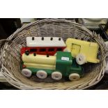 AN OVAL WOVEN WICKER BASKET CONTAINING A PAINTED THREE-PIECE TOY TRAIN