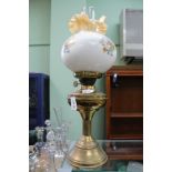 A BRASS BASED OIL LAMP with floral decorated globular shade