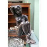 A SIGNED BRONZED NAKED SEATED FEMALE FIGURINE, indistinctly signed