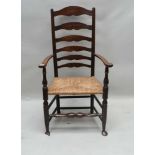 A 19TH CENTURY COUNTRY VERNACULAR LADDER BACK ARMCHAIR with rush seat, 111cm high
