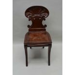 A 19TH CENTURY MAHOGANY HALL CHAIR with well carved scallop shell back and solid seat, having reeded