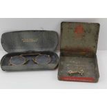 A YELLOW METAL BRACE in old tin and a PAIR OF YELLOW METAL FRAMED PINCE NEZ, cased