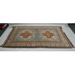 A WOVEN WOOL EAGLE KAZAKH (CHELABERD KARABAGH) PATTERNED FLOOR RUG with a pale blue central ground