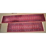 TWO WOVEN WOOL FLOOR RUNNERS, on a pigeon red ground, having central field of elephants feet,