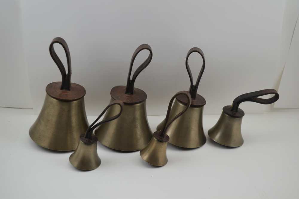 A SET OF SIX HAND BELLS, with butler straps, the leather caps embossed 'GW', (Probably for the