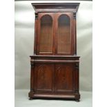 A 19TH CENTURY MAHOGANY BOOKCASE having shaped pediment over twin arched glazed doors, revealing