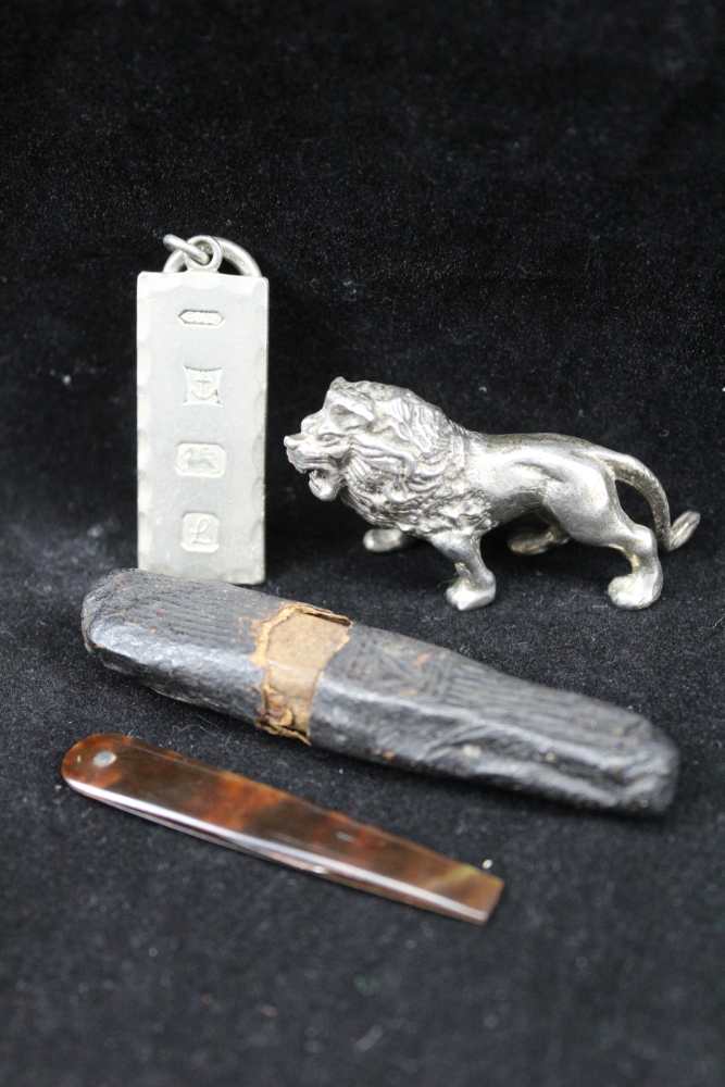 A CAST SILVER LION, 3cm high a silver ingot pendant, combined weight; 83g, together with a