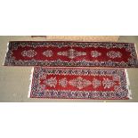 A PAIR OF WOVEN WOOL FLOOR RUNNERS on a claret red ground, with stylised blue floral centres and