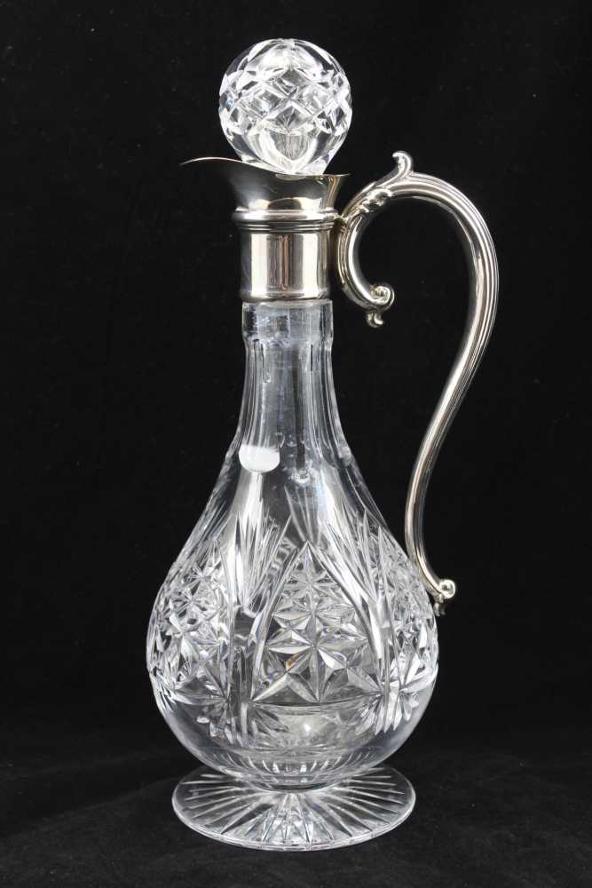 A CUT GLASS CLARET JUG with plated collar and handle, raised on circular star cut base, 30cm high,