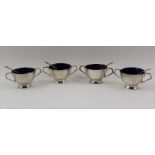 A SET OF FOUR EDWARDIAN SILVER SALTS of circular two handled design, fitted blue glass liners,
