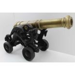 A MODEL GUN CANNON with ring turned brass barrel, on a cast iron dragon decorated base with four