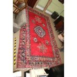 A LARGE ROOM SIZED WOVEN WOOLLEN FLOOR CARPET, having central red ground field with geometric