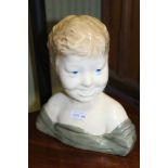 A CONTINENTAL POTTERY BUST OF A CHILD, 29cm high, (factory mark inside)